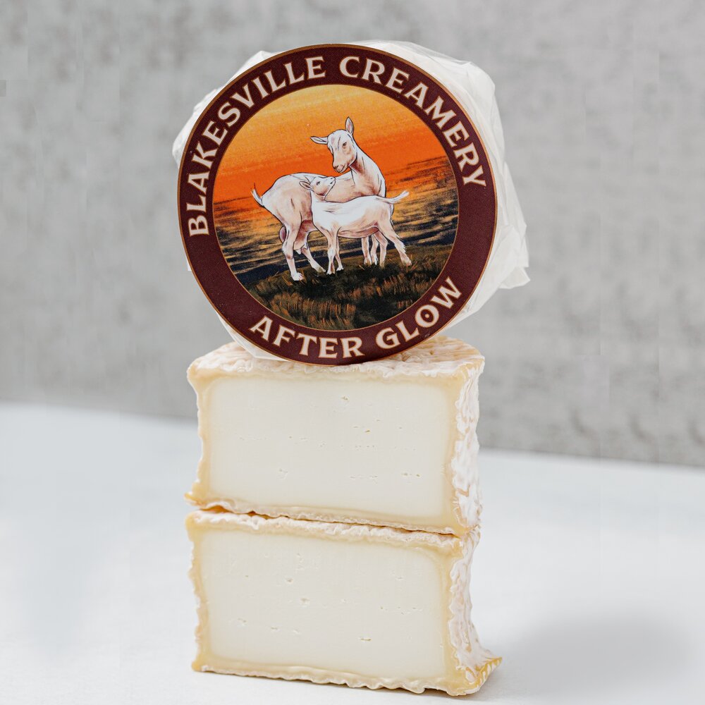 one whole cheese wheel of Afterglow, with another wheel cut in half below