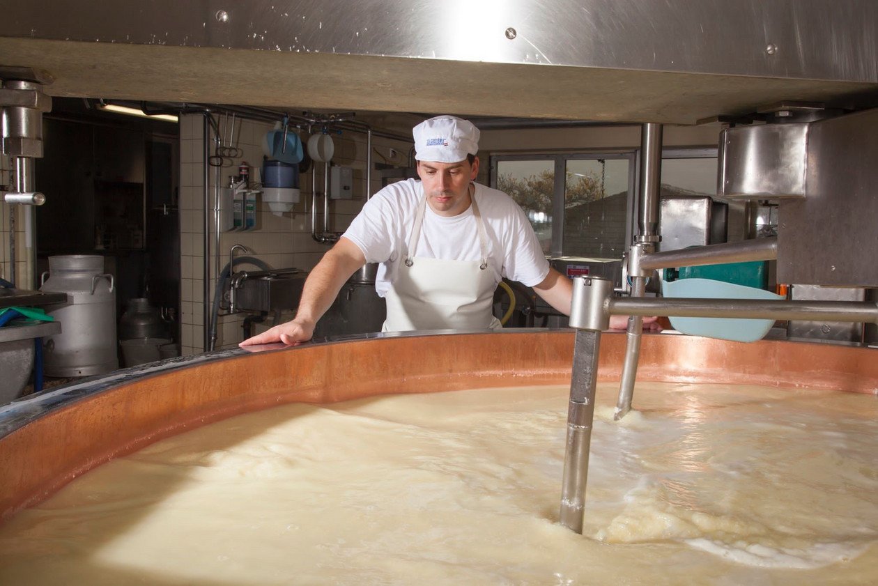 Person working with a large vat of liquid in a kitchen setting