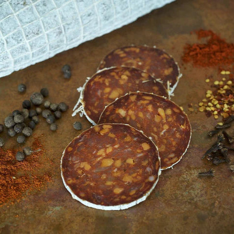 Sliced salami with various spices on a rustic surface