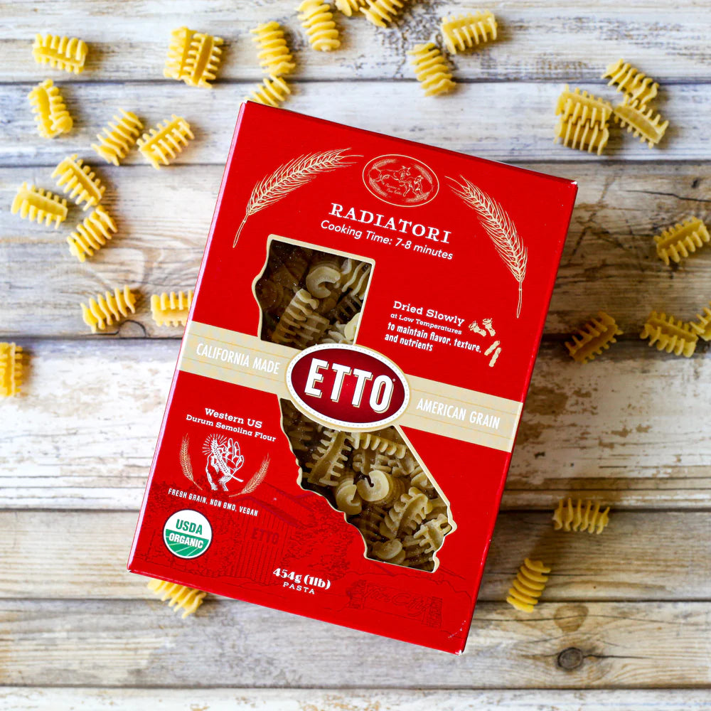 red box of pasta, with pasta spread across wooden table