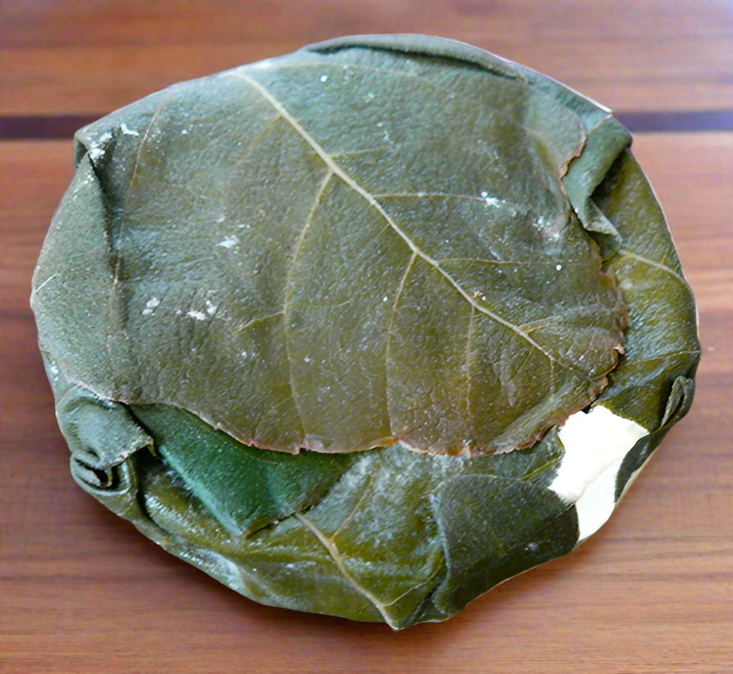 wheel of figaro cheese, wrapped in grape leaves