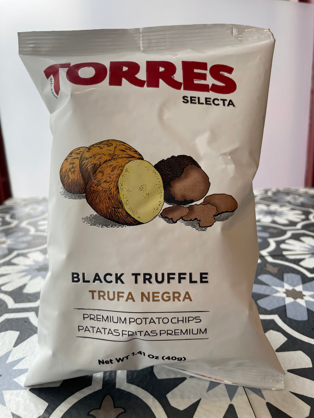 Front side of potato chips "torres selecta" black truffle chips on a patterned surface
