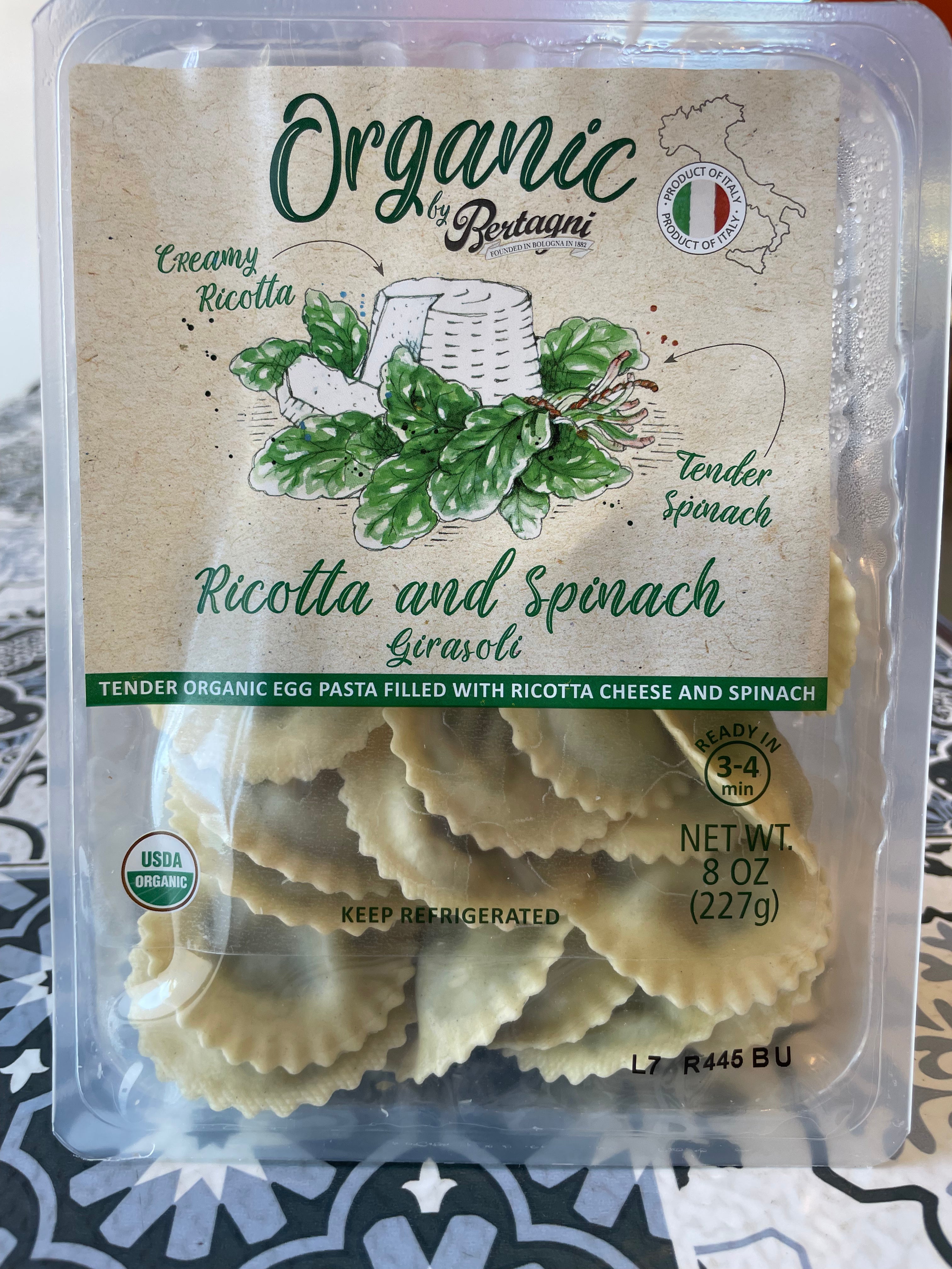 Packaged organic ricotta and spinach pasta with branding on a patterned surface