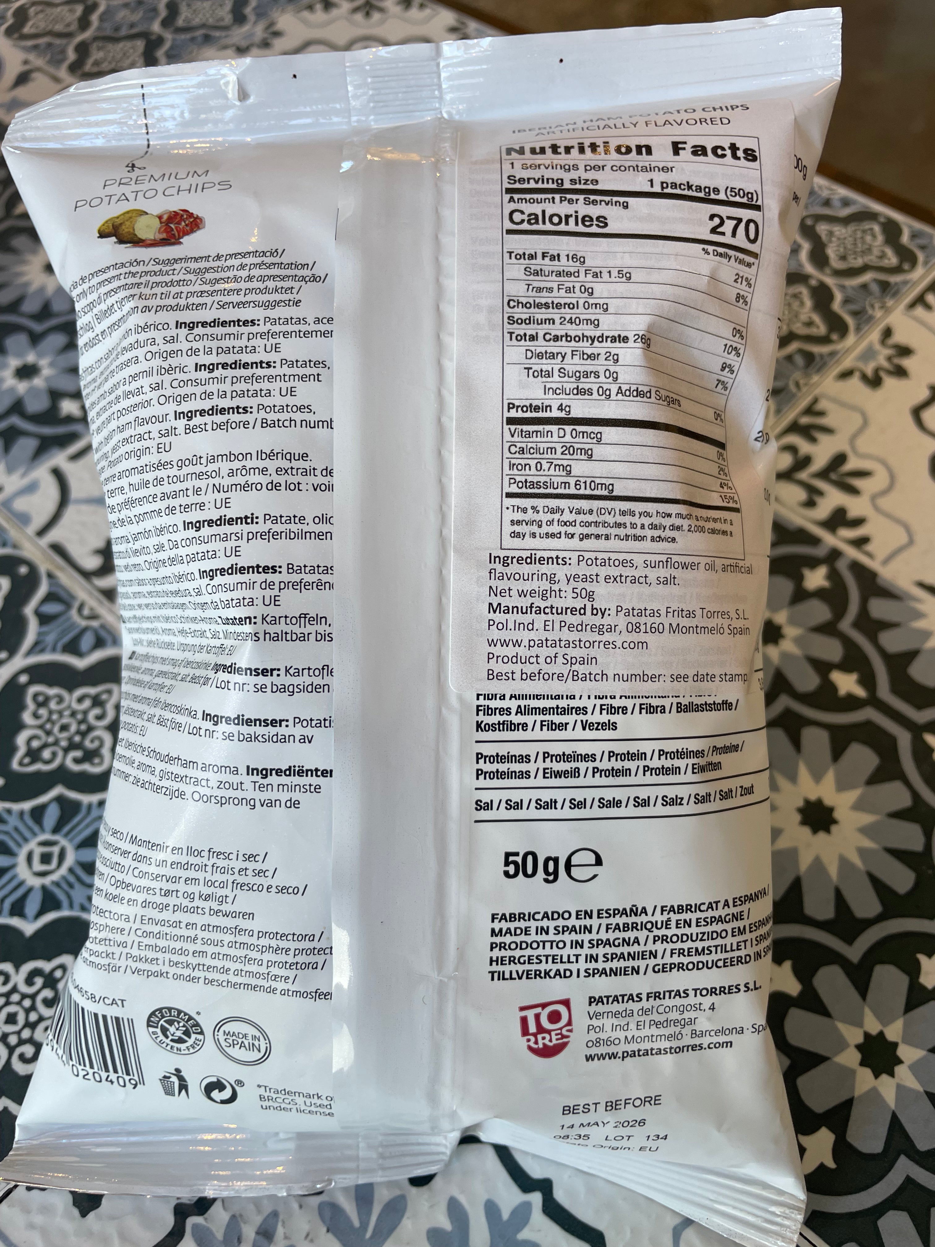 Back view of a potato chip package showing nutrition facts and ingredients on a patterned surface.