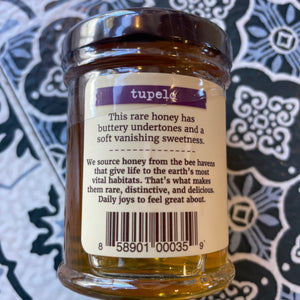 Jar of Tupelo honey with a label Showing how it is sourced, on a patterned background
