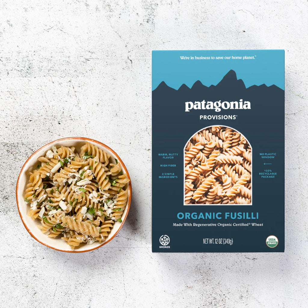 Patagonia Provisions Organic Fusilli pasta box next to a bowl of pasta on a textured surface
