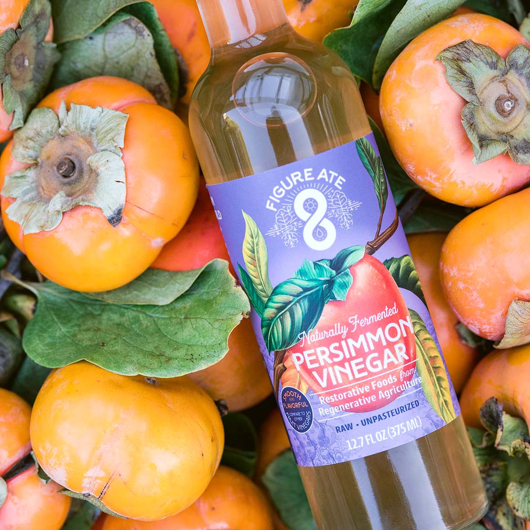 Glass bottle of persimmon vinegar, with persimmons all around
