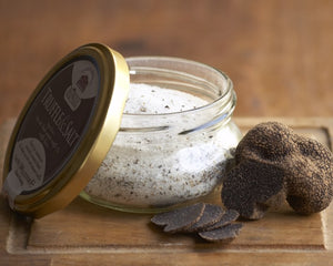 open glass jar of truffle salt, with full sized truffles next to it