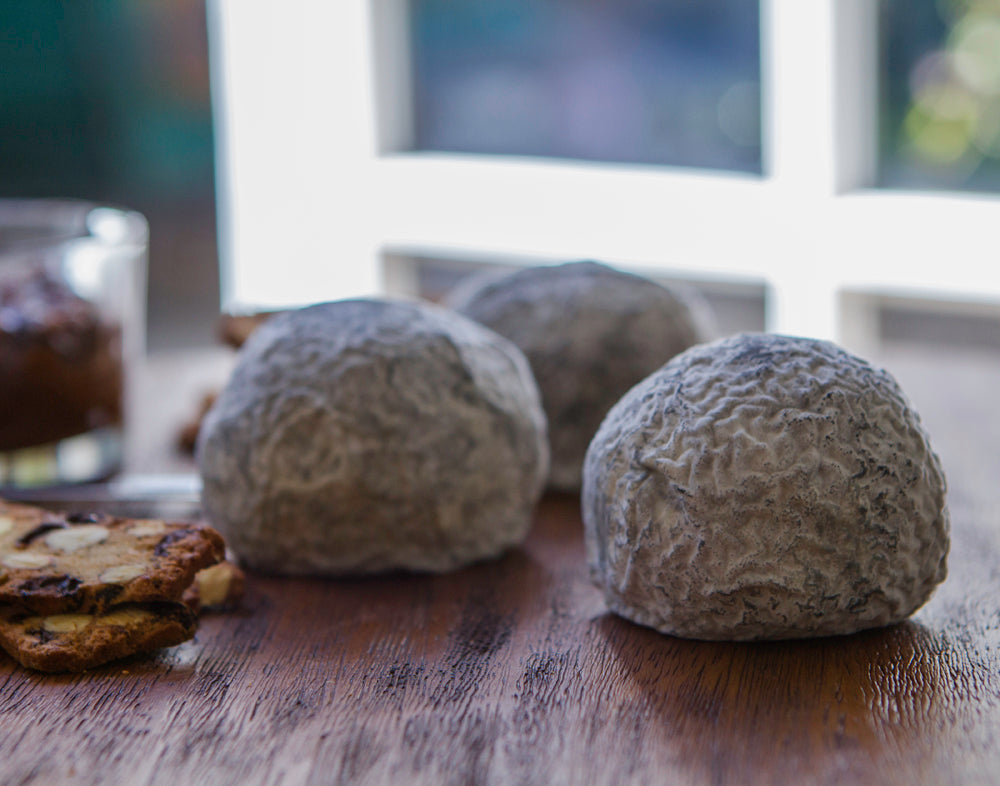 Three textured wrinkley cheese balls with a grey surface, with a blurred background