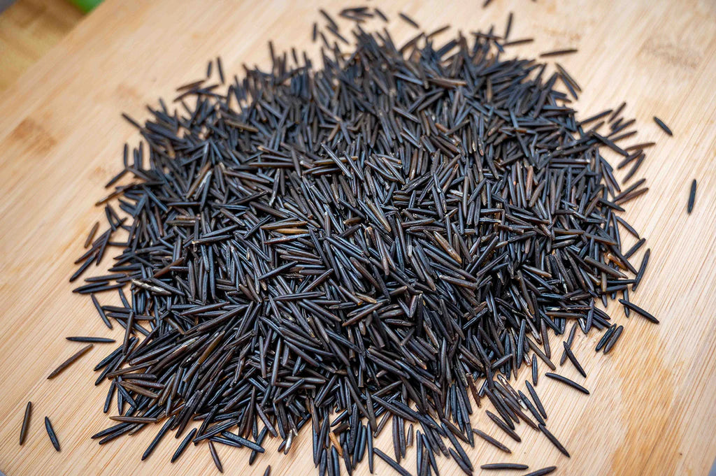 Black long strands of wild rice, in a cluster on top on the wooden