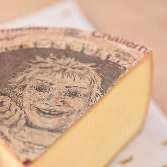 Large wheel of alpine cheese with a picture of a face on the label