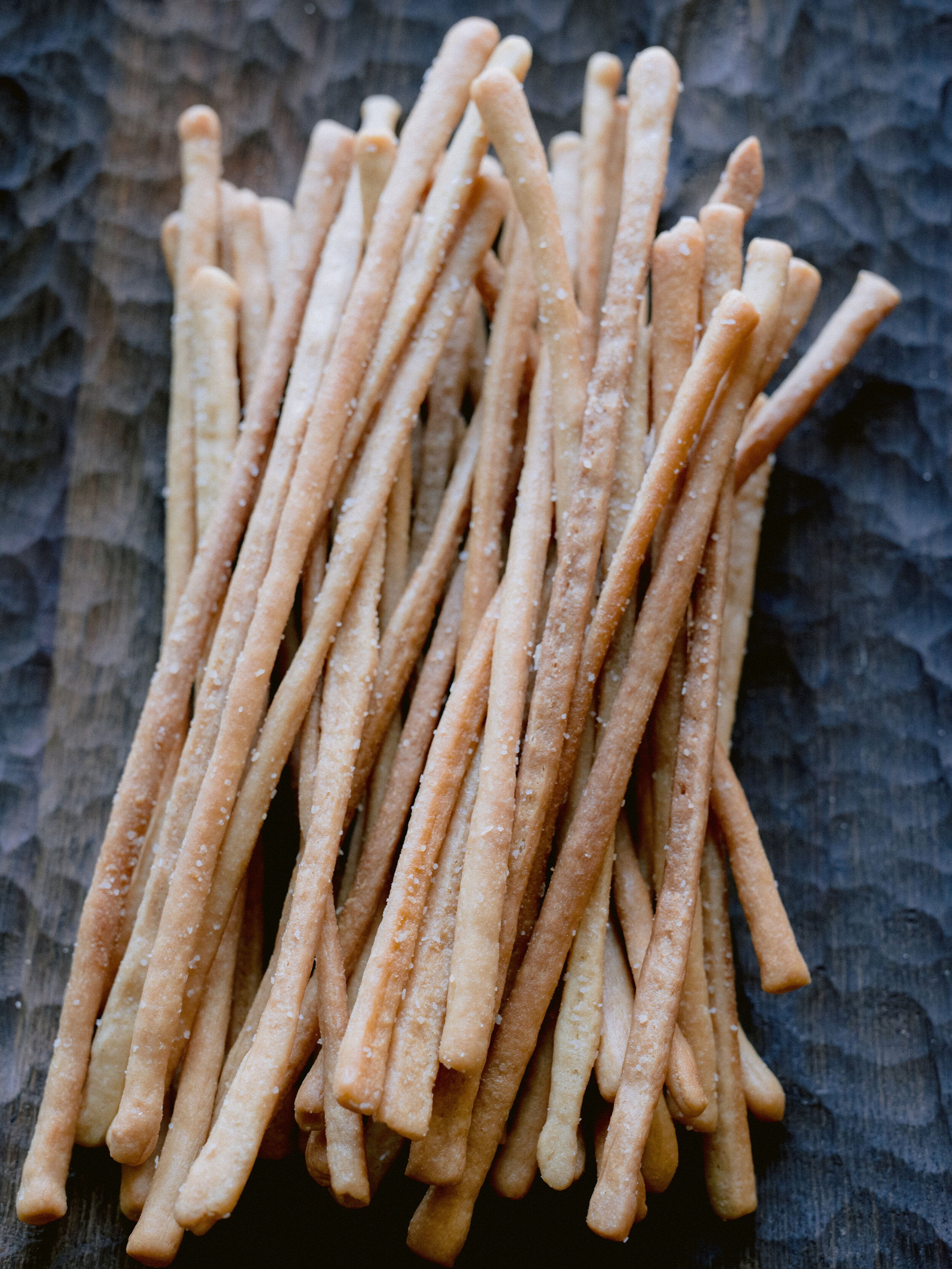 Pile of thin hand rolled breadsticks with sea salt