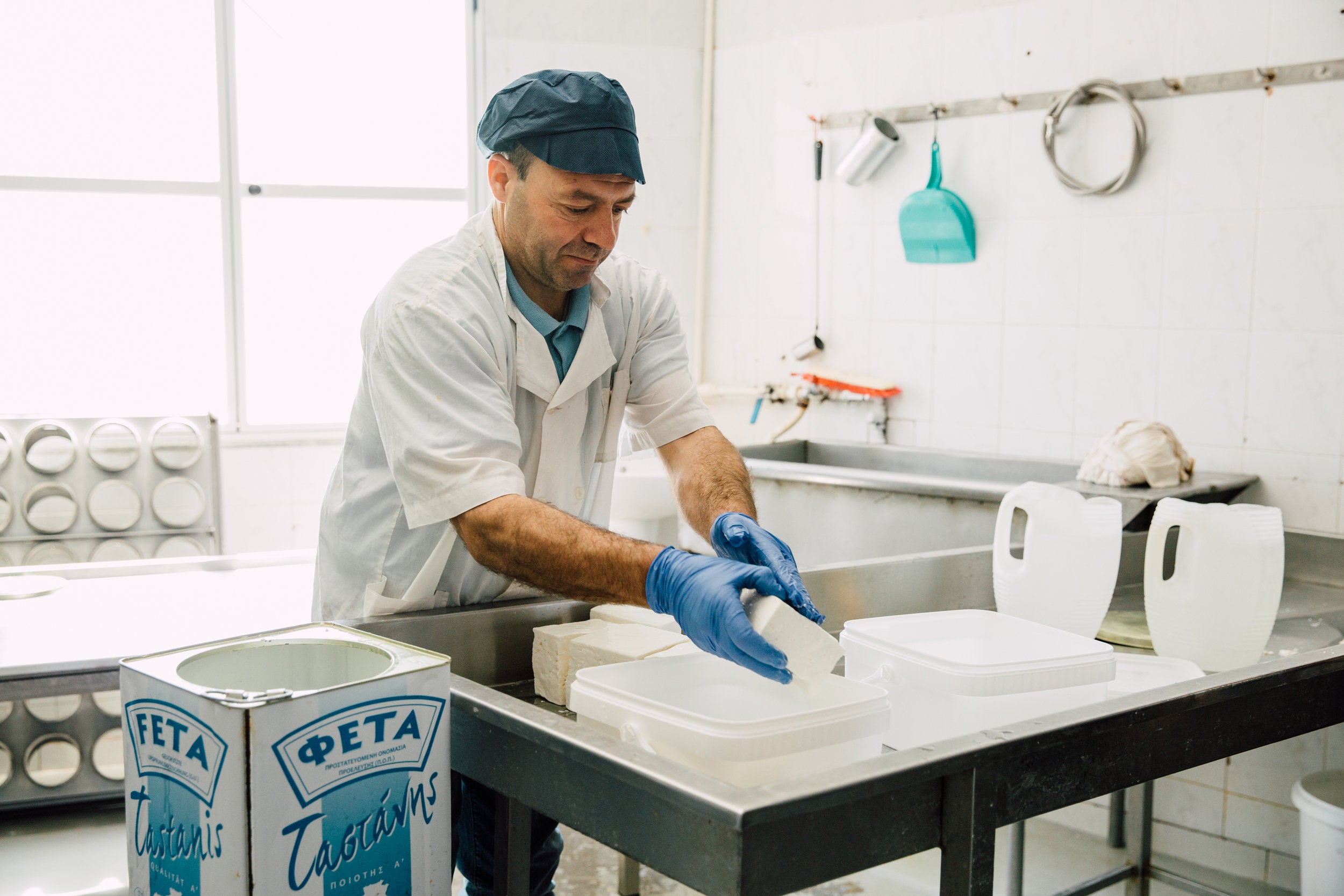 man cutting and packaging feta in producer warehouse