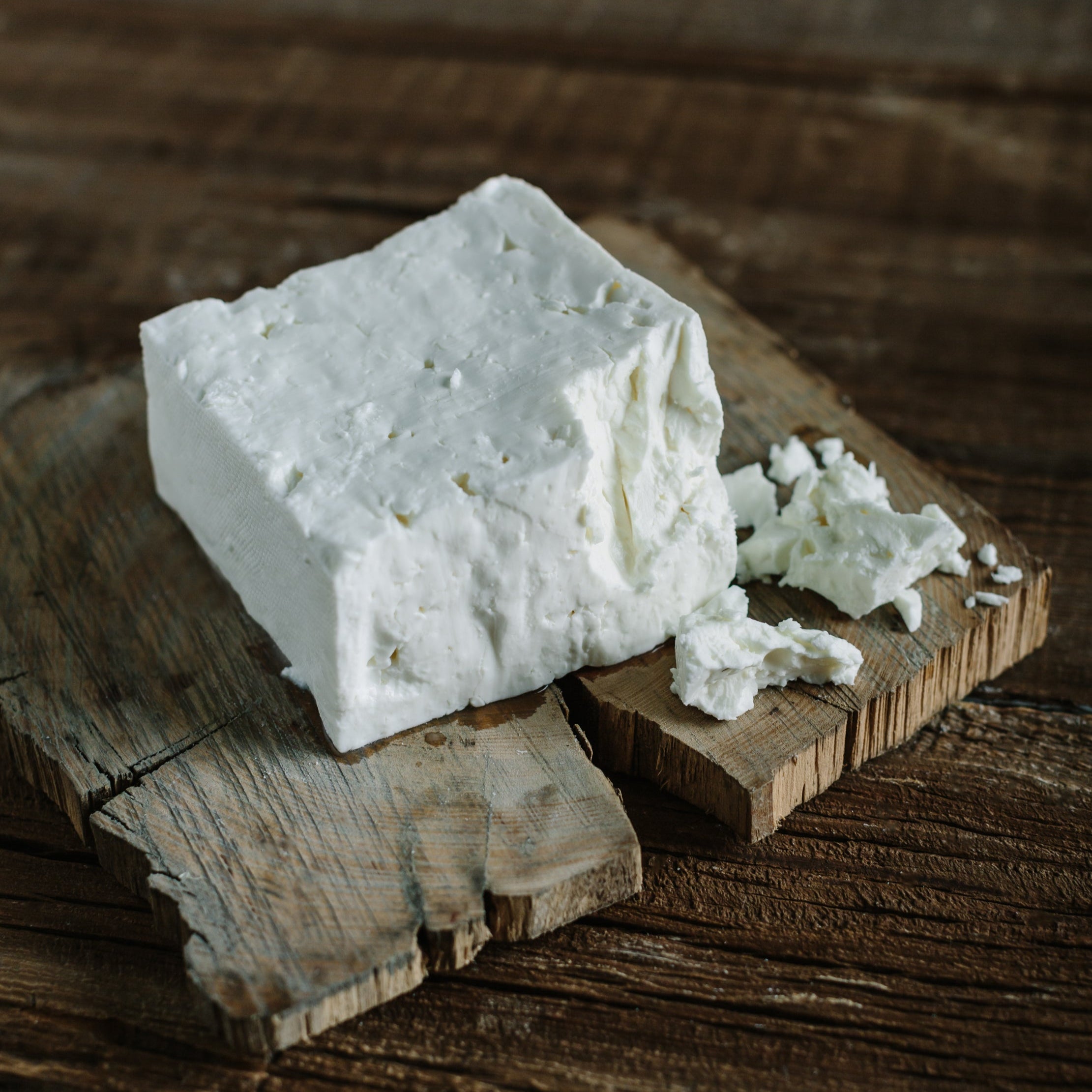 block of white feta cheese, crumbly pieces falling off