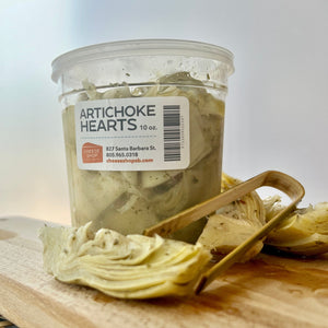plastic container of artichoke hearts in olive oil, with a pair of tongs
