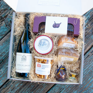 inside of gitbox with bottle of red wine, container of snack mix, three chunks of cheese, crackers, and pairing items