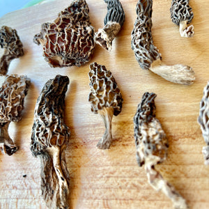 close up of dried morel mushrooms on wooden board