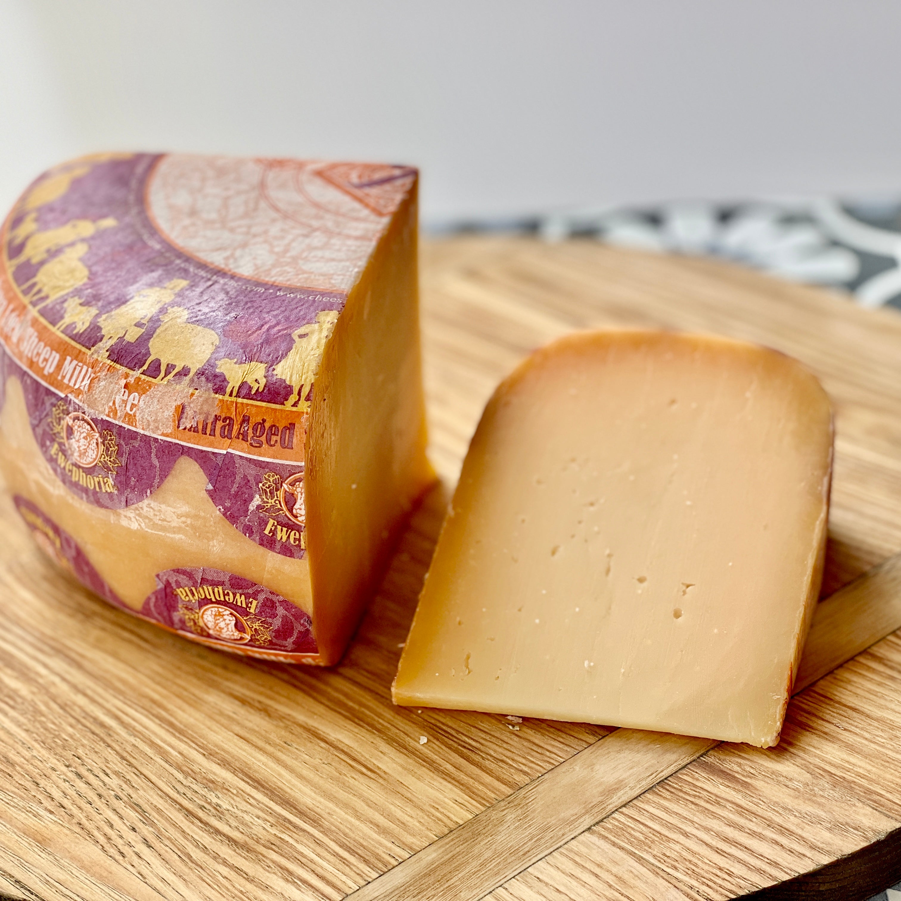 quarter wheel and wedge of light orange sheep's milk cheese