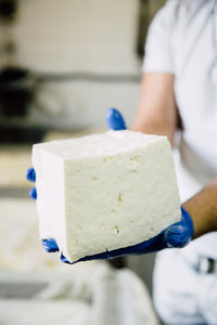 man holding massive block of feta