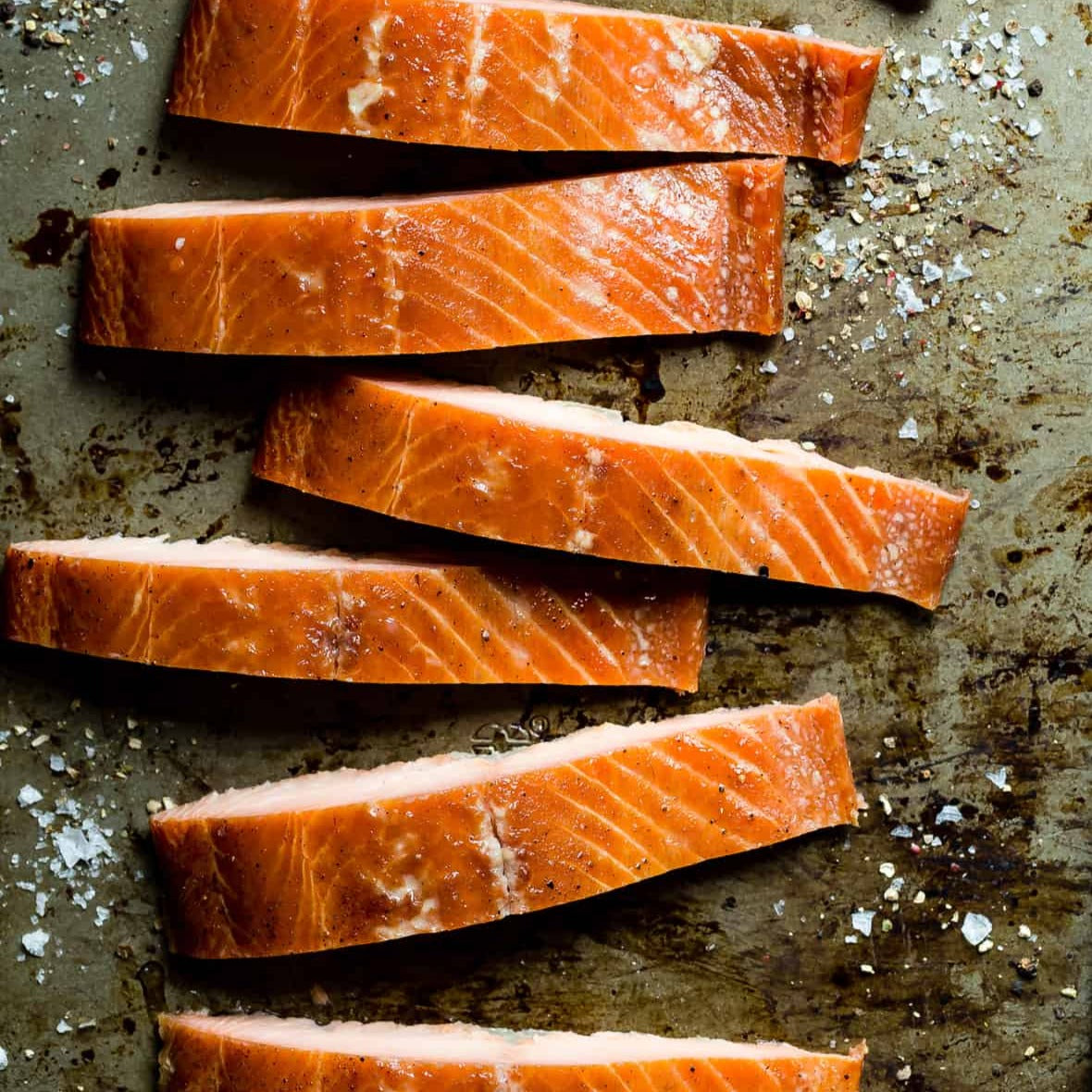 several pieces of hot smoked salmon on a baking pan with flaky salt