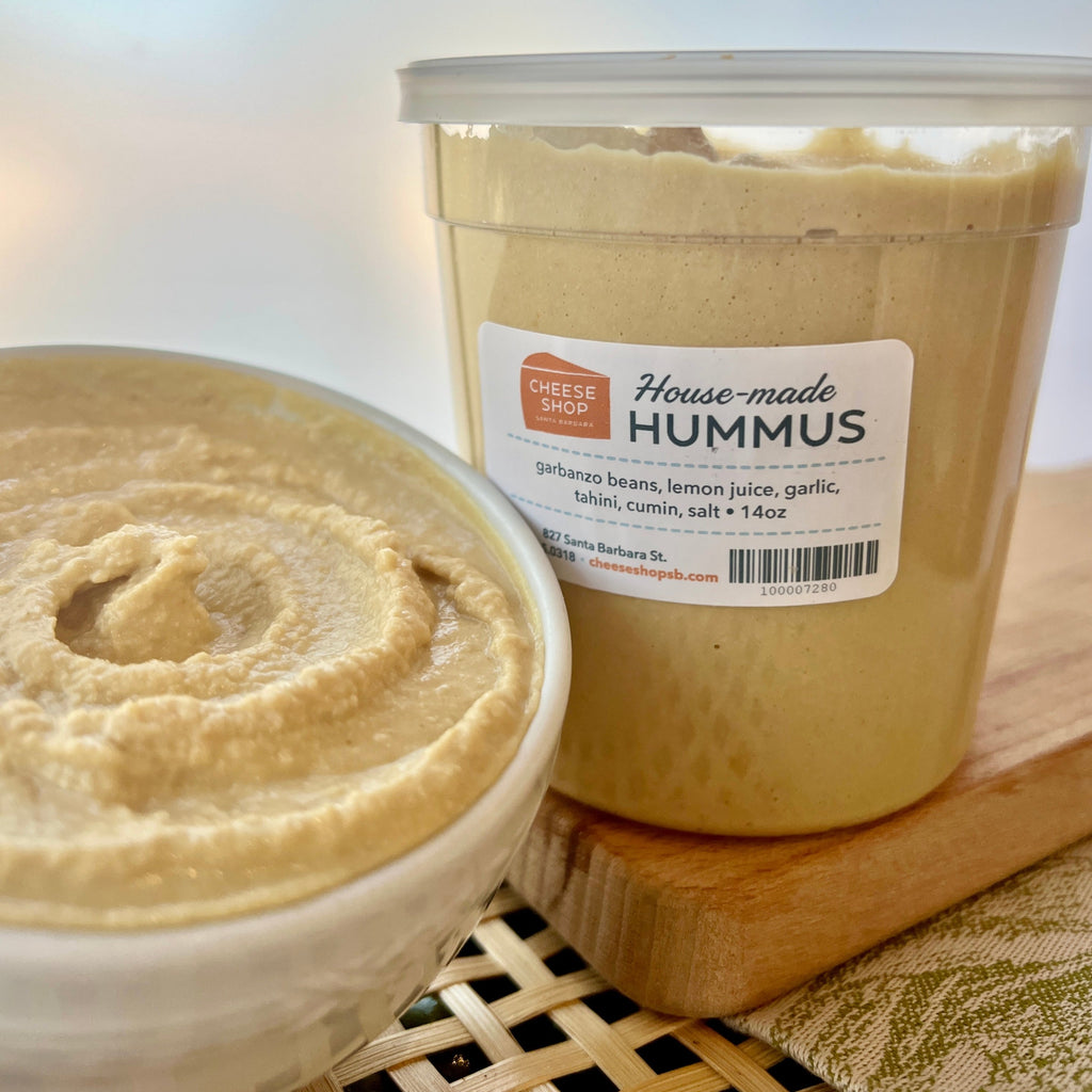 plastic container and ceramic bowl of housemade hummus