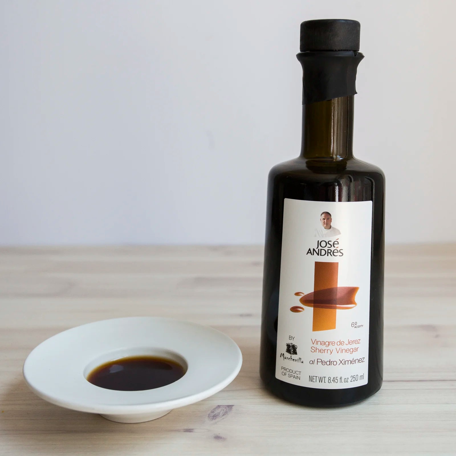 glass bottle of sherry vinegar, with sherry vinegar in white ceramic bowl