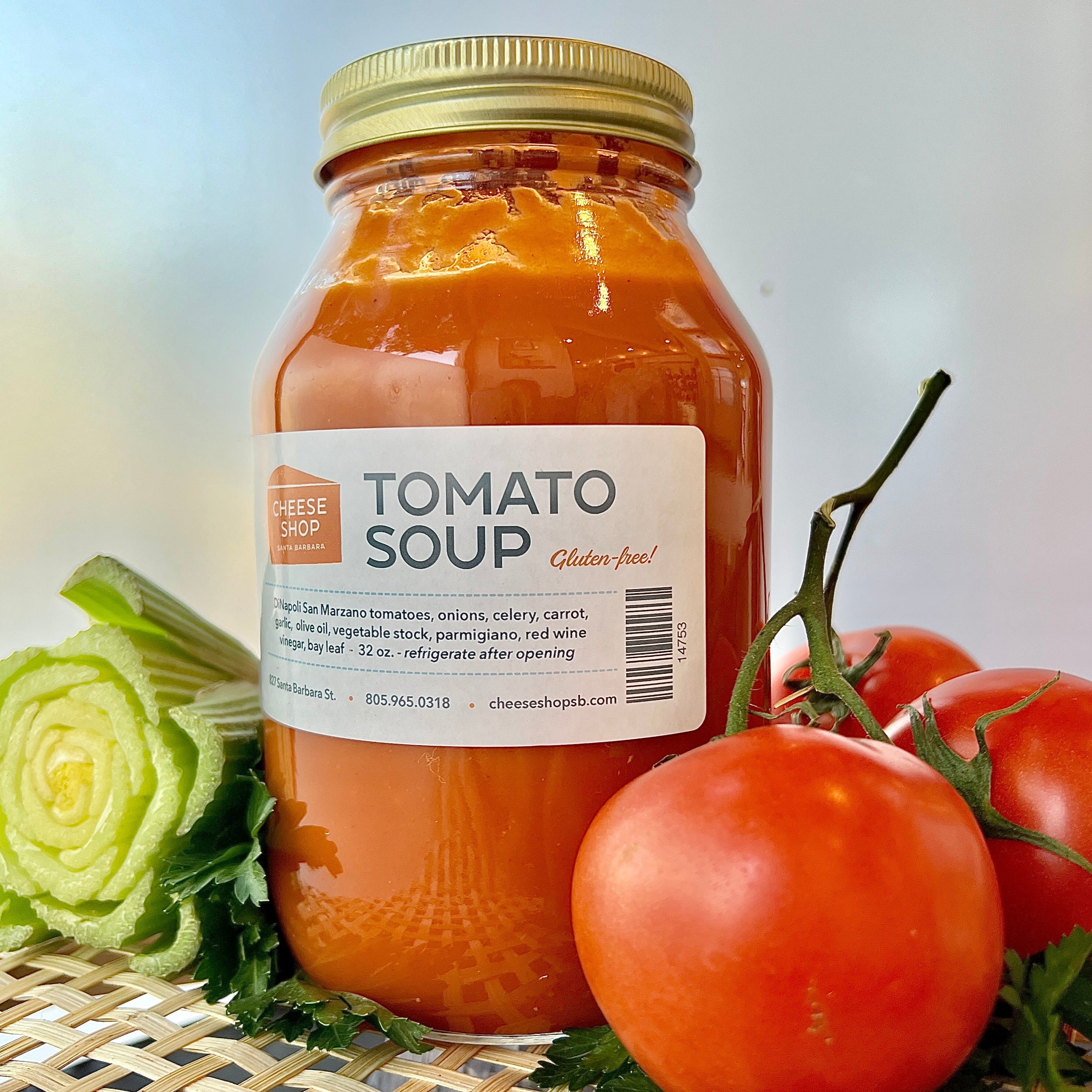 32oz glass mason jar of housemade tomato soup, with tomatoes and celery around